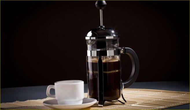 French press se šálkem kávy na černém pozadí